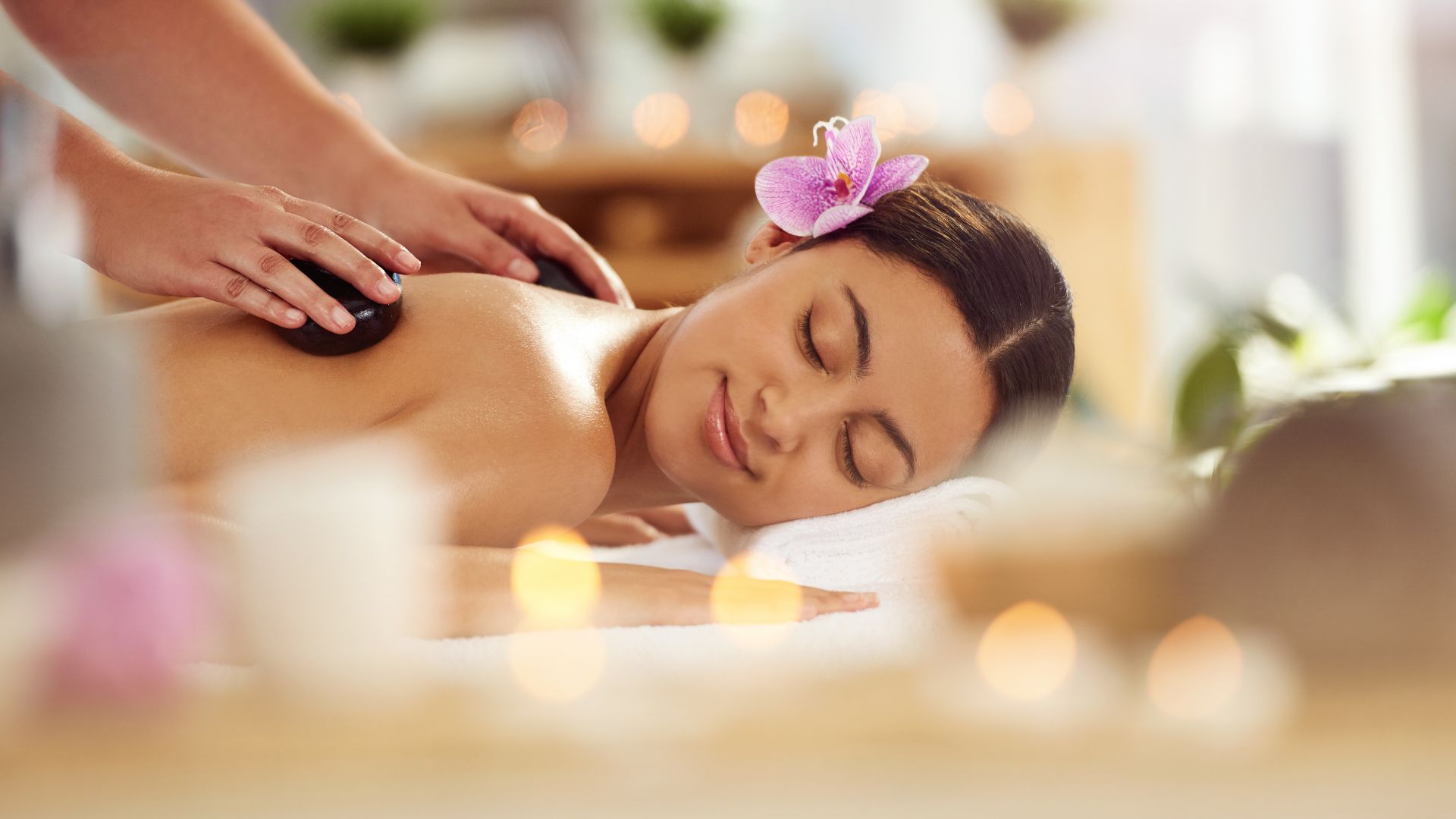 woman with flower in hair receiving massage
