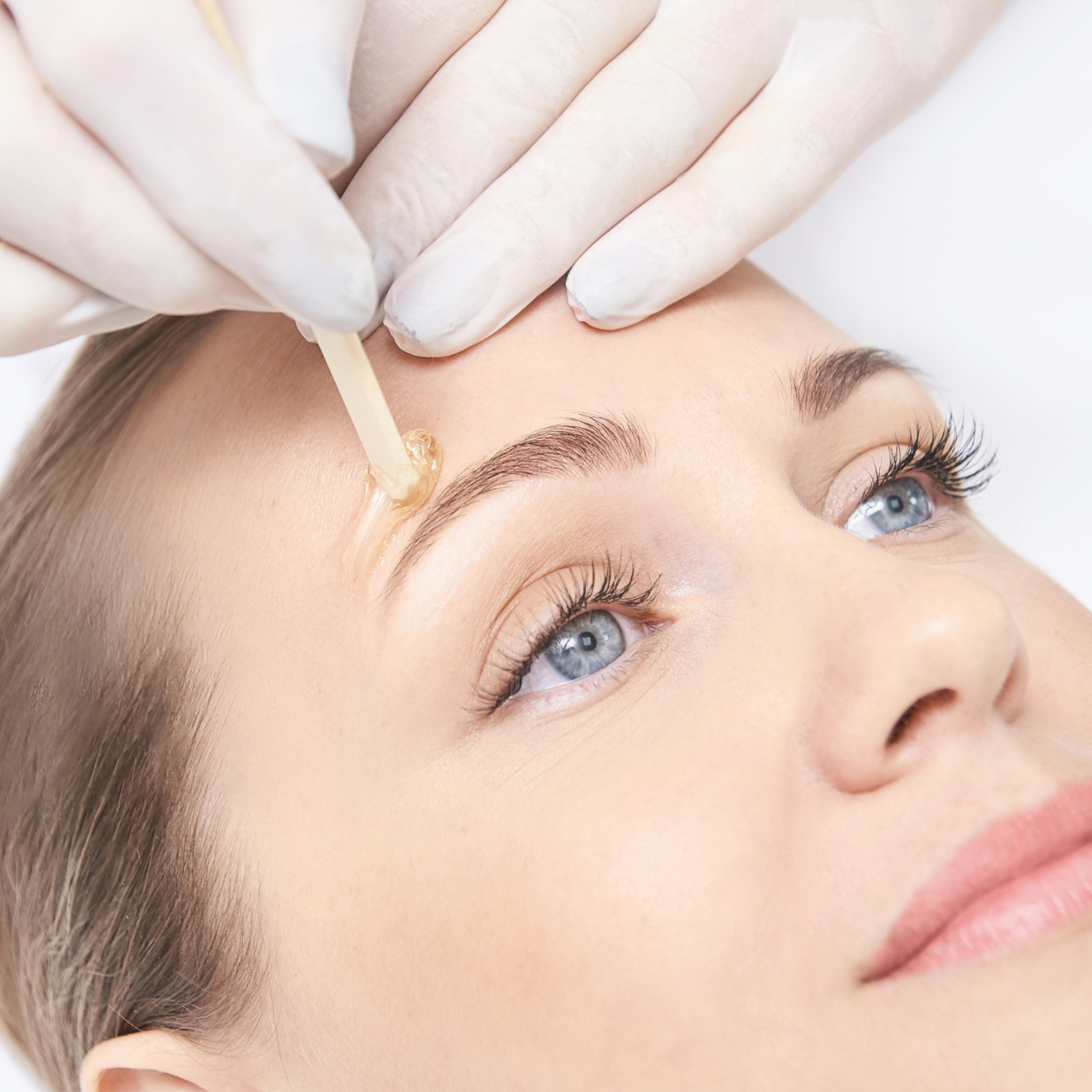 Woman receiving eyebrow waxing treatment